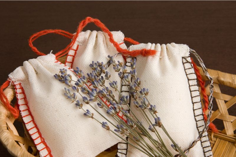 3 drawstring scented sachets with flowers lying on top of them 