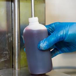 a gloved hand filling a bottle with liquid