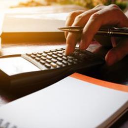 a man holding a pen and using a calculator to calculate the costs of contract packing